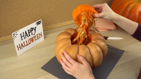 Womens-hands-pull-out-the-cap-and-make-a-hole-in-the-Halloween-pumpkin