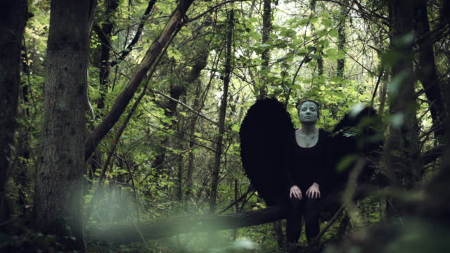 4k-Halloween-Dark-Angel-Frau-mit-schwarzen-Flügeln-im-Wald-sieht-nach-oben-und-nach-Kamera