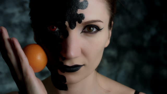 4-k-Aufnahme-einer-Frau-mit-Halloween-Make-up-Rollen-eine-Orange-auf-Gesicht