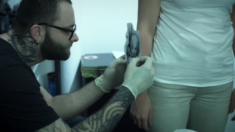 4-k-Tattoo-Künstler-Vorbereitung-Zeichnung-auf-Client-Arm