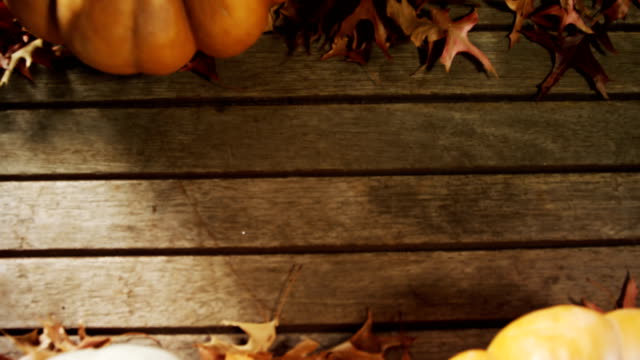 Halloween-Kürbis-mit-Ahornblatt-auf-einem-Holztisch-4k