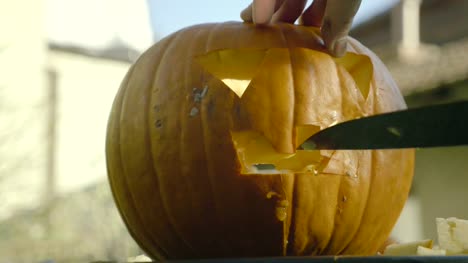 Father-carves-with-knife-Halloween-creepy-head.-Man's-hands-carve-knife-the-pumpkin-spooky-mouth-with-teeth.