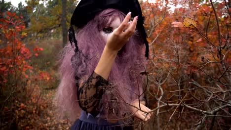 Jóvenes-rosa-pelo-bruja-en-reactivos-de-la-búsqueda-sombrero-en-el-místico-bosque-de-otoño.-Preparación-de-Halloween.