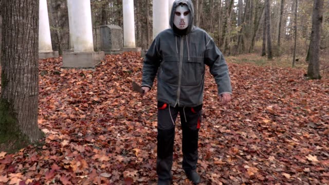 Mann-in-scary-Halloweenmaske-und-Machete-zu-Fuß-vor-der-Kamera