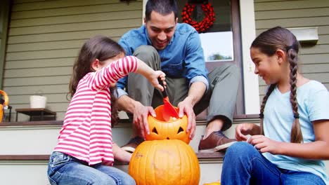 Vater-und-Töchter-Halloweenkürbis-auf-Haus-Schritte-schnitzen