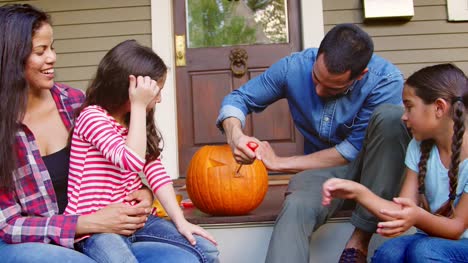 Family-Carving-Halloween-Pumpkin-On-House-Steps