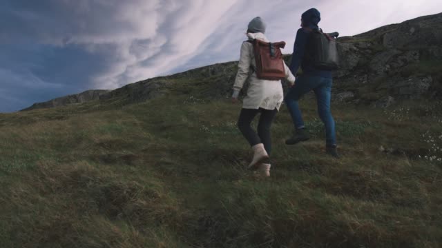 Young-loving-couple-walking-in-field-on-background-of-epic-dramatic-clouds,-slow-motion