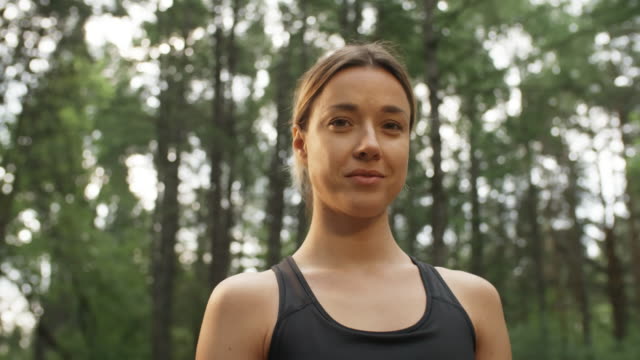 Porträt-von-fröhlichen-Sportlerin-im-Wald-stehen