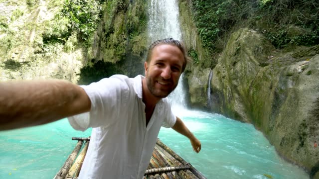 Junger-Mann-umarmt-schönen-Wasserfall-in-den-Philippinen
