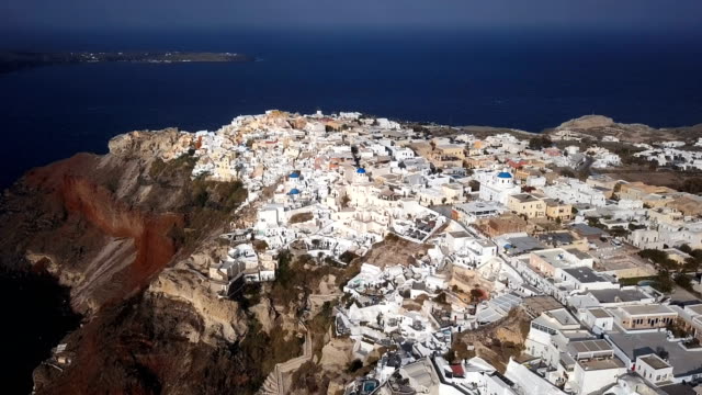 Sobrevuelo-de-la-ciudad-de-Oia-al-atardecer,-isla-de-Santorini,-Grecia