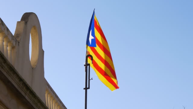 sun-light-blue-sky-España,-bandera-meciéndose-al-viento-4-K-barcelona