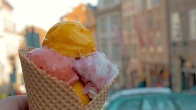 Slow-motion-view-of-unfocused-cityscape-on-the-background-and-then-seen-ice-cream-balls-in-the-waffle-cup,-Prague,-Czech-Republic
