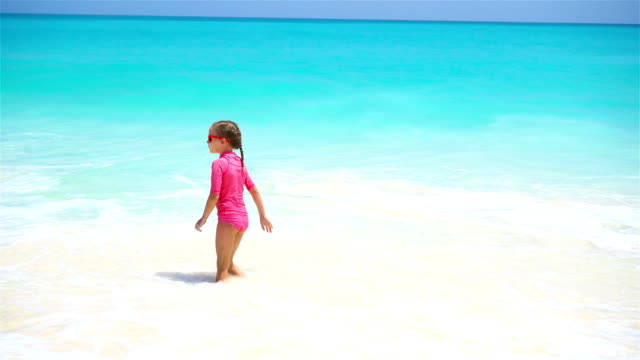 Entzückende-kleine-Mädchen-am-Strand-mit-einer-Menge-Spaß-im-Wasser