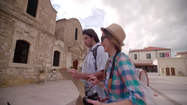 Young-couple-with-map-walking-around-old-stone-built-village
