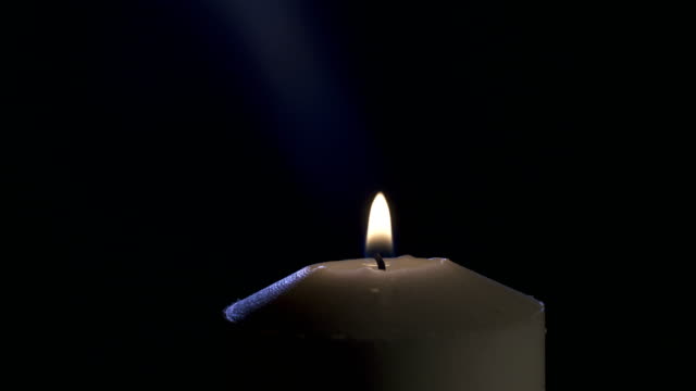 Slow-Motion-Makro-Aufnahmen-von-einer-weißen-Kerze-beleuchtet-durch-ein-Match-auf-einem-dunklen-Hintergrund