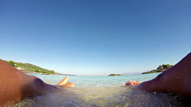 Schöne-gebräunte-Frauen-Beine-am-Strand-ein-Sonnenbad-nehmen.---SOMMER-KONZEPT