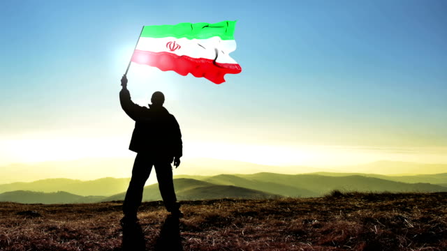Erfolgreiche-Silhouette-Mann-Sieger-winken-Iran-Flagge-oben-auf-der-Bergspitze,-4-k-Cinemagramm
