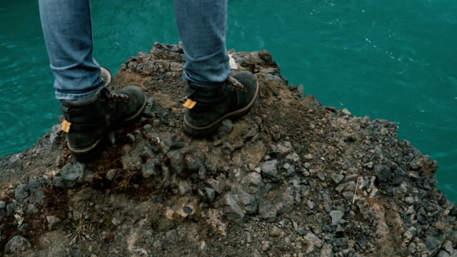 Joven-parado-en-la-roca-cerca-de-una-cascada-de-gran-alcance-en-Islandia-y-mirando-caer-el-chorro-de-agua