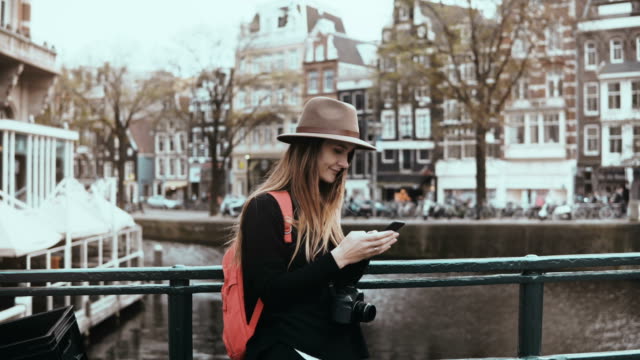 Pretty-lady-uses-social-networks-on-smartphone.-4K.-Adult-30s-European-female-with-long-hair-in-hat-types-a-message