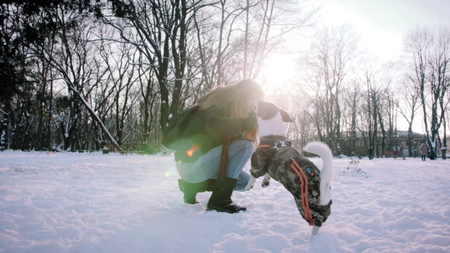 Joven-jugando-con-Jack-Russell-terrier-en-época-de-invierno-en-la-nieve,-cámara-lenta
