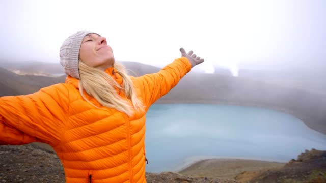 Young-woman-arms-outstretched-at-spectacular-crater-lake-in-Iceland