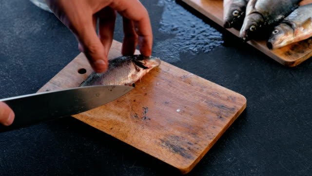 Man-cuts-the-fins-of-the-carp-fish.-Cooking-fish.-Hands-close-up.