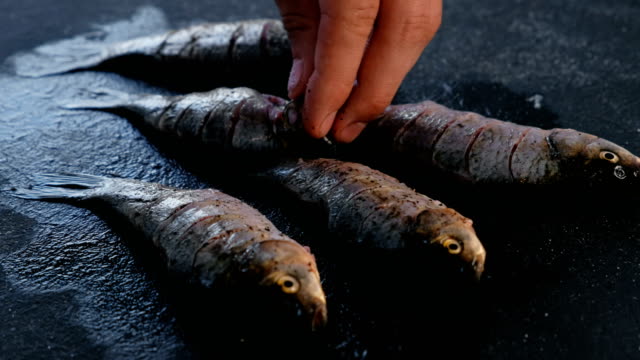 Man-salt-a-carp-fish-on-the-black-table.-Cooking-fish.-Hand-close-up.