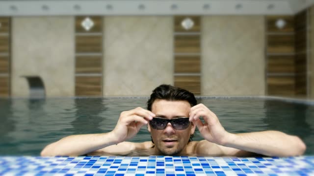 Man-swims-in-the-pool-in-sunglasses.