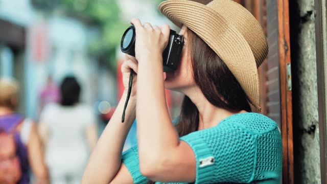 Happy-face-of-female-tourist-in-hat-taking-photo-using-professional-camera