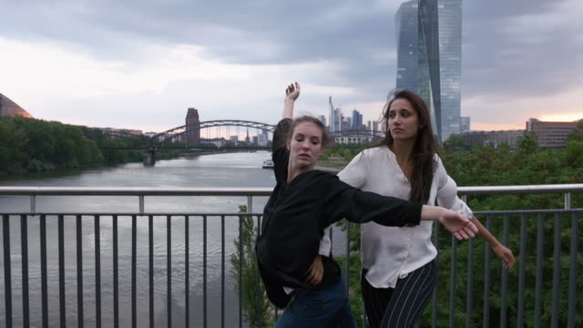 Mädchen-tanzen-nebeneinander-auf-Stadtbrücke