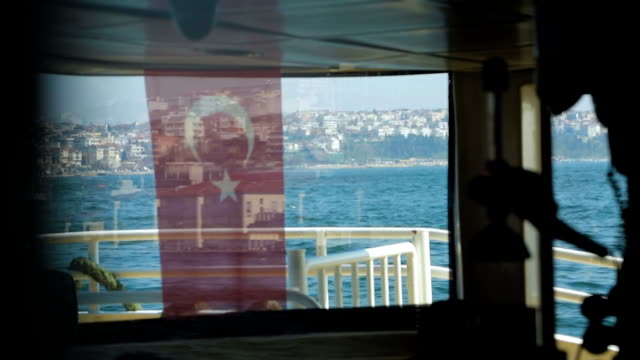 Watching-view-through-Turkish-flag-on-board-of-tourist-vessel,-public-transport