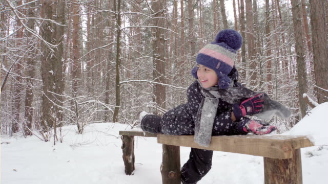Mädchen-liegend-auf-einer-Holzbank-im-winter