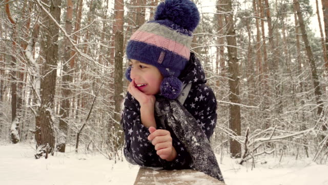 Girl-lying-on-a-log-on-the-background-of-the-winter-forest