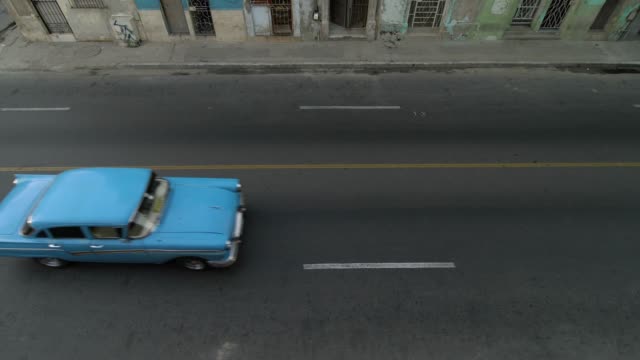 high-angle-aerial-establishing-shot-of-classic-car-on-Malecon-street-of-Havana,-Cuba