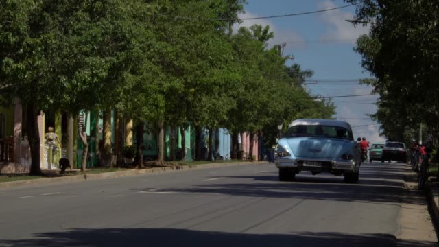 Cuban-classic-1950's-american-vintage-car-driving-on-the-street-of-rural-town-Vinales-valley,-Cuba