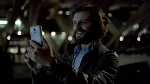 Young-Caucasian-man-having-video-call-on-smartphone-at-night