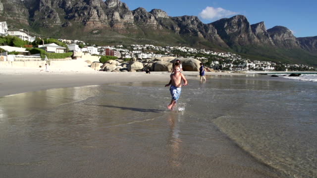 Slow-motion-of-young-boy-running-towards-the-camera-along-the-beach,South-Africa