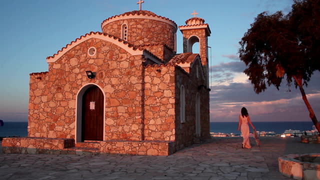 Beautiful-Greek-woman-walking-near-old-church,-looking-at-amazing