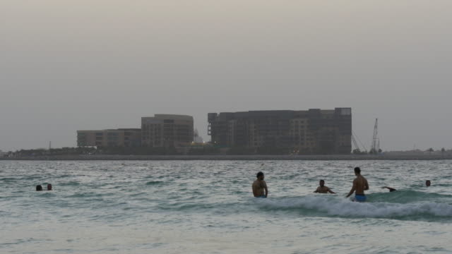 Por-la-noche,-los-Emiratos-Árabes-Unidos-swimers-Dubai-Palma-Hotel-con-una-vista-de-la-construcción-4-K