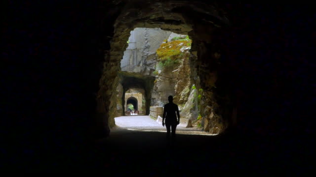 Abandoned-Train-Tunnels,-Woman-Walks-From-Dark-into-Light,-1800s-Railroad
