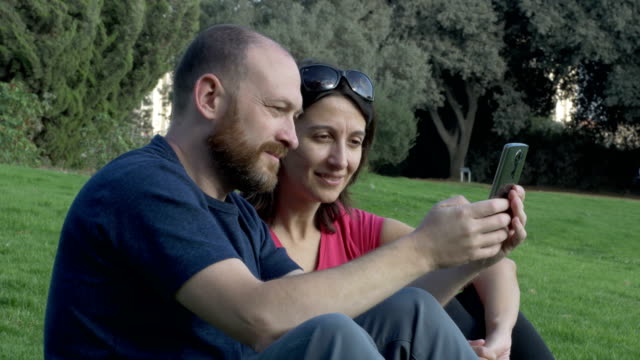Glückliches-Paar-mit-Smartphone-im-Park