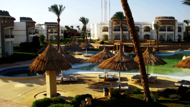 Sunny-Hotel-Resort-with-Blue-Pool,-Palm-Trees-and-Sunbeds-in-Egypt
