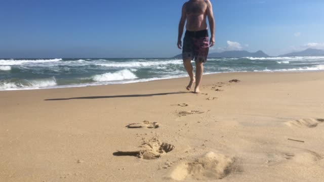 Man-walking-at-the-beach-coming-to-camera