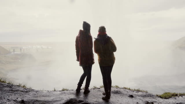 Vista-posterior-de-dos-mujer-feliz-junto-a-la-Gljufrabui-en-Islandia.-Viajar-mujer-explorando-los-lugares-de-interés