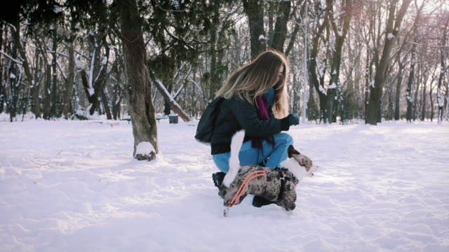 Young-woman-playing-with-Jack-Russell-terrier-in-winter-time-in-snow,-slow-motion