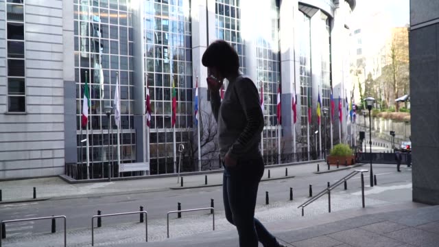 lady-is-walking-and-talking-on-the-phone-near-the-European-Parliament-in-Brussels.-Belgium.-slow-motion