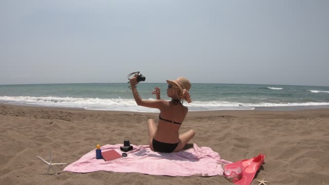 Mujer-sexy-en-bikini-sentada-y-divertirse-en-la-playa.