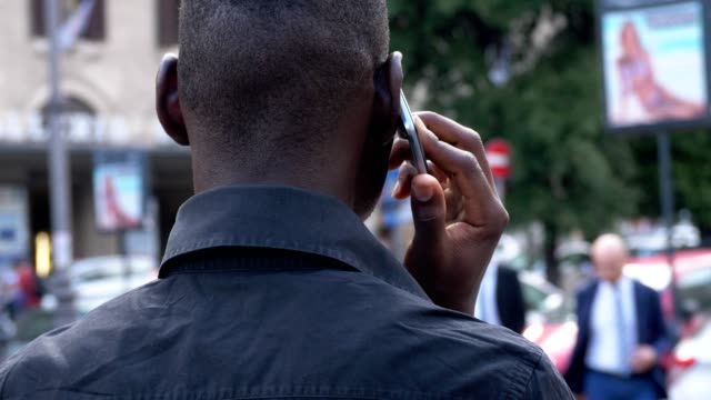 Junge-schwarze-Afrikaner-in-der-Stadt-sprechen-von-Telefon-Rückansicht