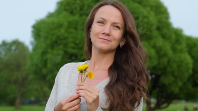 Romantic-adult-woman-with-small-dandelions-in-countryside