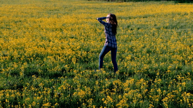 Brünette-Frau-geht-auf-dem-Gebiet-der-gelben-Blüten.